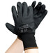 A pair of hands wearing black Cordova Cor-Touch gloves with black foam nitrile and polyurethane coating.
