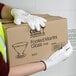 A person wearing Cordova white polyester gloves with white polyurethane palm coating holding a box.