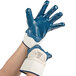 A pair of hands wearing blue Cordova smooth nitrile gloves with white jersey lining.