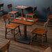A Lancaster Table & Seating wooden table and chairs in a restaurant dining area with napkins on it.