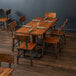 A Lancaster Table & Seating solid wood live edge dining table with chairs and napkins in a restaurant dining area.