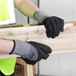 A person wearing Cordova Conquest safety gloves holding a piece of wood.