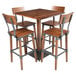A Lancaster Table & Seating live edge wood bar table with four chairs around it.