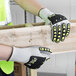 A person wearing Cordova OGRE-CR safety gloves holding a piece of wood.