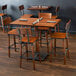 A Lancaster Table and Seating wooden bar height table with chairs in a restaurant.