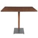 A Lancaster Table & Seating bar height table with a wooden top and metal base.