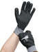 A person wearing gray Cordova warehouse gloves with black coating and nitrile dots.