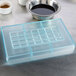 A Matfer Bourgeat polycarbonate tray with a square grid in each compartment holding liquid.