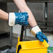 A person wearing Cordova Brawler smooth supported nitrile gloves holding a yellow mop.