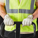 A person wearing Cordova Select Grain Pigskin Leather driver's gloves and a safety vest holding a hand truck.
