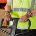 A person wearing Cordova leather warehouse gloves using a hand truck.
