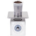 An Edlund stainless steel metric portion scale with a plastic container full of coffee beans on the platform.