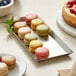 A rectangular stainless steel tray with colorful macaroons on a table.