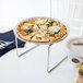 A Choice chrome metal pizza stand with a pizza on a table.