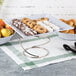 An Acopa stainless steel metal display stand with cookies and apples on it on a table in a bakery.