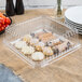A clear plastic Fineline square catering tray with food on it.