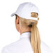 A woman wearing a white Chef Revival baseball cap with a black logo and a ponytail.
