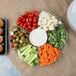 A Fineline clear plastic tray with 7 compartments of vegetables and dip on a table.