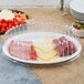 A Fineline white plastic oval catering tray with cheese, meat, and vegetables on it.