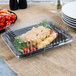 A Fineline black plastic rectangular catering tray filled with tomatoes and carrots.