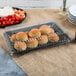 A Fineline black plastic rectangular cater tray with rolls and vegetables on it.