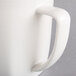 A close up of a Hall China bright white mug with a handle.