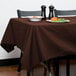 A table with a brown Intedge tablecloth and a plate of food.