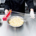A person in a chef's uniform using SC Johnson Saran Premium plastic wrap to cover a bowl of noodles.