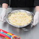 A person holding a bowl of pasta wrapped in SC Johnson Saran Premium plastic wrap.