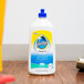 A white bottle of SC Johnson Pledge Squirt and Mop Multi-Surface floor cleaner with a blue and yellow label on a wood surface.
