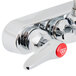A T&S chrome wall mounted faucet with red and chrome lever handles.