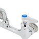 A chrome T&S wall mount faucet with lever handles and a blue knob.