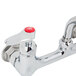 A T&S chrome wall mount faucet with lever handles and red accents.