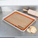 A baking tray with cookies and a Sasa Demarle SILPAT&reg; baking mat on a metal surface.