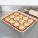 A tray of cookies on a Sasa Demarle SILPAT quarter size baking mat with a wooden rolling pin.