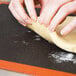 A person's hands rolling out dough on a Sasa Demarle full size perforated silicone baking mat.