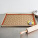 A Sasa Demarle SILPAT baking mat with macaron circles and a rolling pin on it.