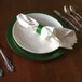 A white Tabletop Classics by Walco charger plate with a green napkin on it.