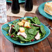 A Fiesta® Turquoise square luncheon plate with a salad of spinach, mushrooms, and cranberries on it.
