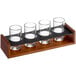A wooden tray with four Acopa Write-On Tasting Glasses on it.