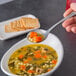 A spoonful of soup with diced carrots in a bowl.