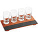 An Acopa flight tray with four tasting glasses on a table in a cocktail bar.