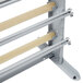 A gray metal rack with wooden poles for holding paper rolls.