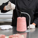 A person using a Bulman red and white thread holder to cut meat with a pink thread.