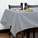 A table with a grey Intedge table cloth and plates of food.