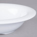 A close-up of a white Carlisle melamine fruit bowl with a rim.