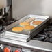 A 12 1/4" x 27" x 4" griddle top with pancakes cooking on a stove.