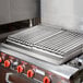 A 24" x 27" x 4" Add-On 4 Burner Charbroiler on a stove with metal grates.