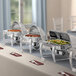 An outdoor buffet table with Acopa stainless steel chafers of food and plates.
