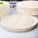 A Town bamboo steamer cover with a woven pattern on a table.